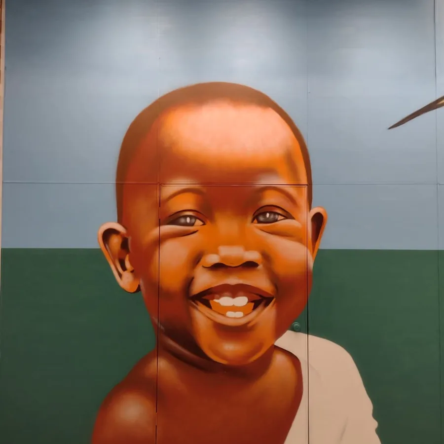 Rosto de bebê sorrindo pintado em grande escala em painel de shopping