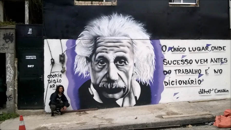 Muro preto com retrato realista de Einstein em preto e branco e uma frase dele ao lado