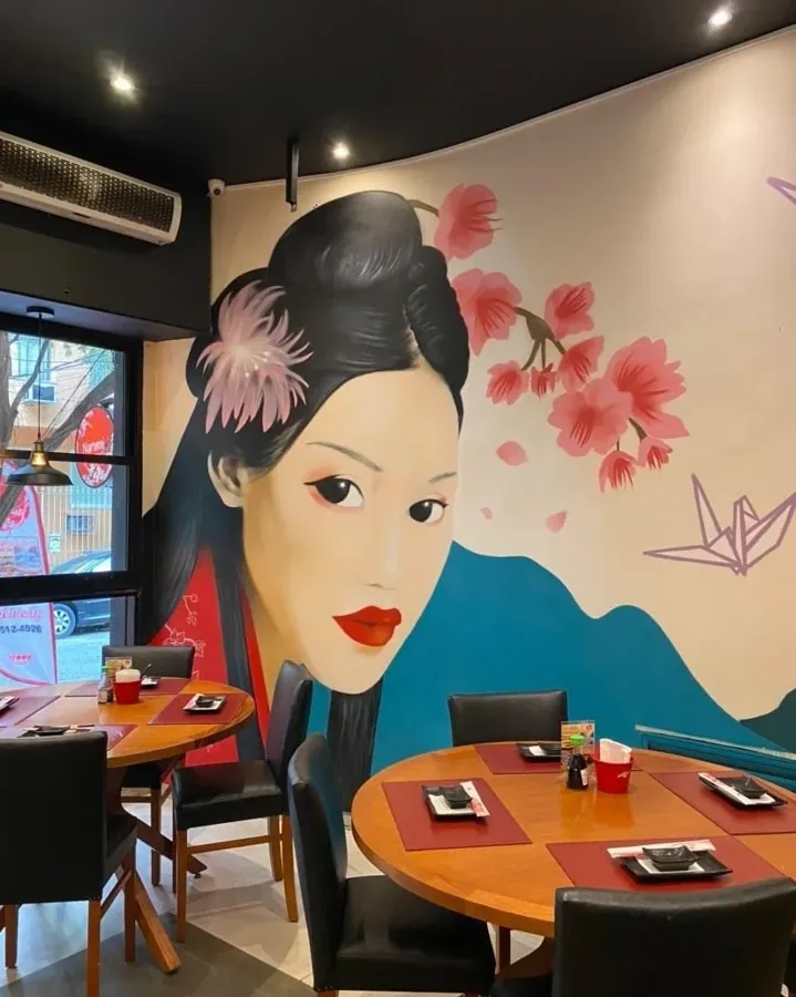 Parede de restaurante japonês com gueixa pintada, flores de cerejeira e tsurus de origami