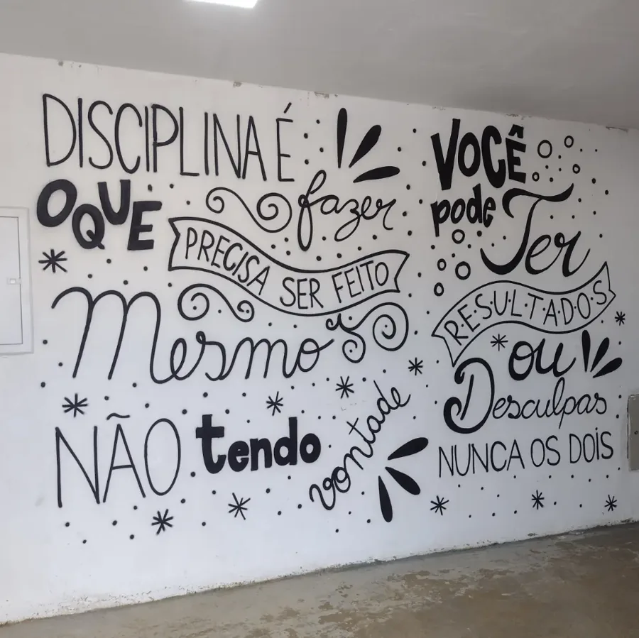 Parede branca com a frase 'Disciplina é fazer o que precisa ser feito mesmo não tendo vontade' em lettering preto
