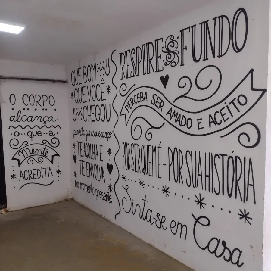 Duas paredes com frases de acolhimento em lettering: 'Respire fundo', 'Sinta-se em casa'