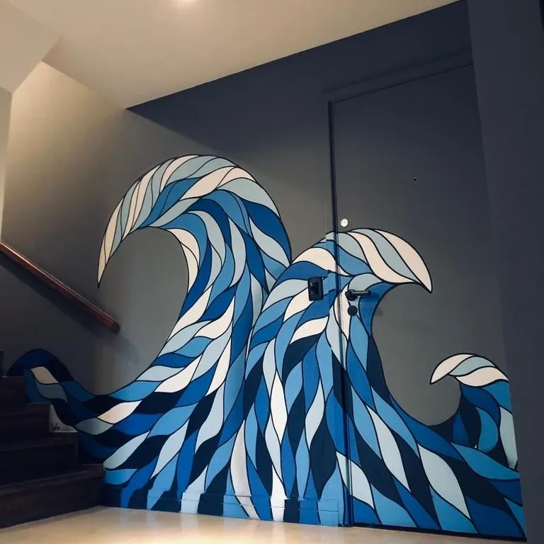 Onda azul em estilo gráfico pintada no canto de uma escada, subindo pela parede e pela porta
