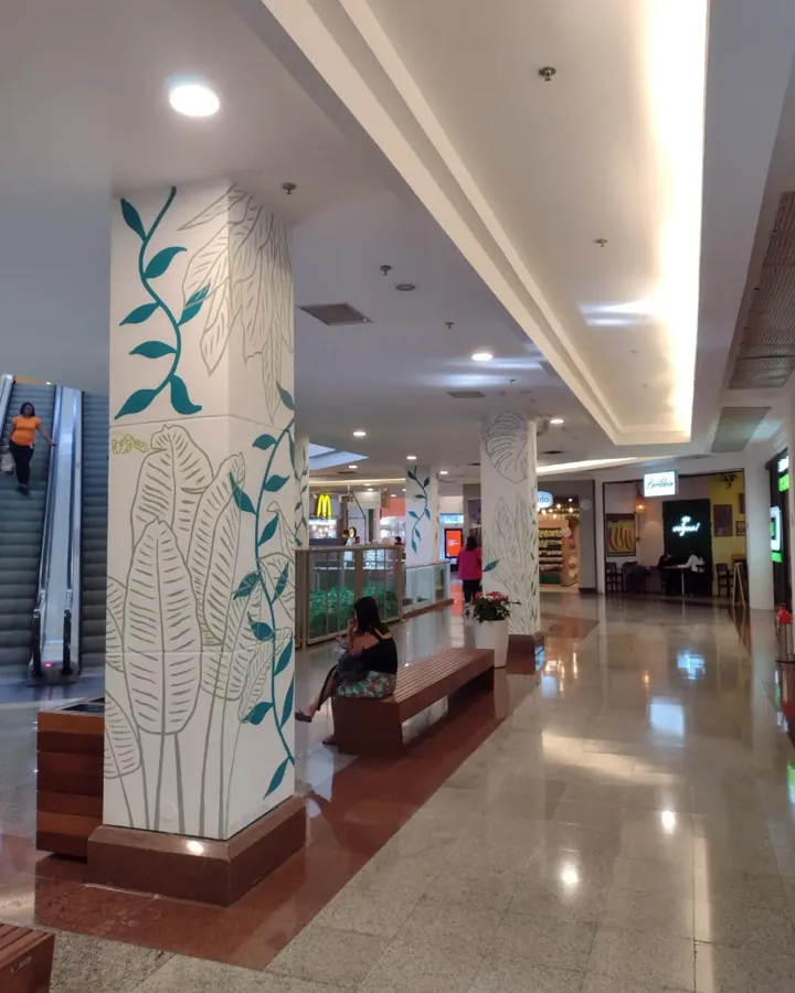 Pilares de shopping pintados com folhagens finas em verde e azul