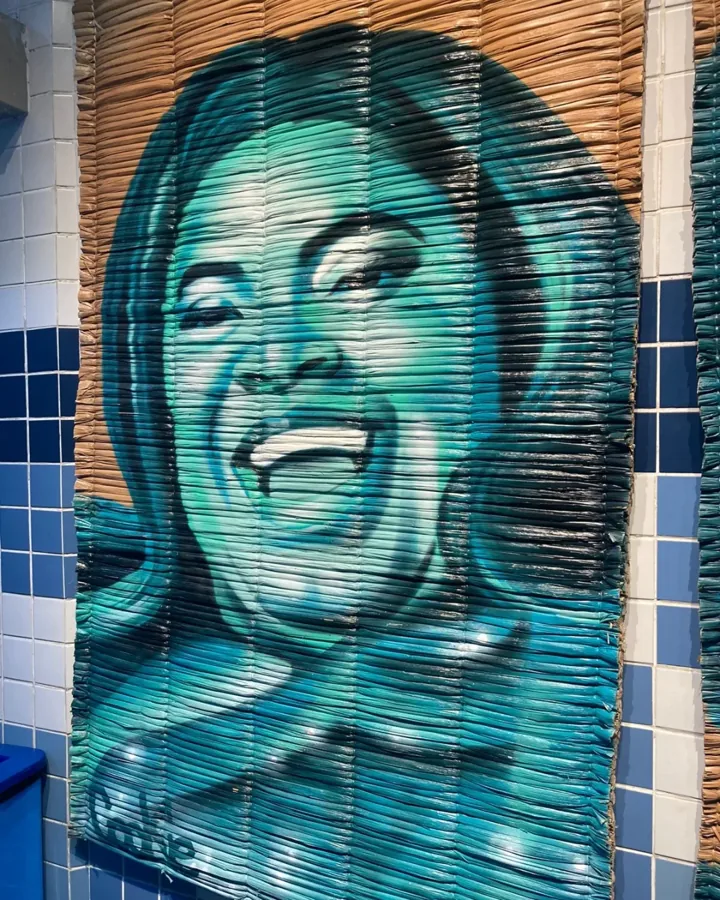 Retrato de mulher rindo pintado em spray azul sobre uma esteira de palha